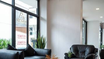 Un intérieur moderne avec un canapé, une table ronde et un luminaire suspendu.