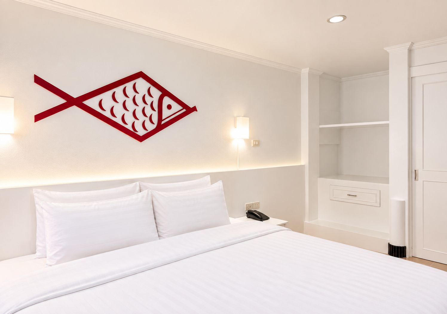 Een hotelkamer met een bed, een wandlamp, een telefoon en een kledingkast.