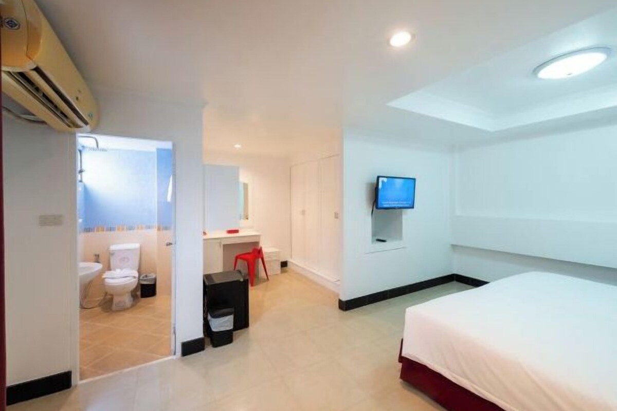 Une chambre d’hôtel équipée d’un lit, d’une télévision, d’un bureau et d’une salle de bain avec des toilettes et un lavabo.
