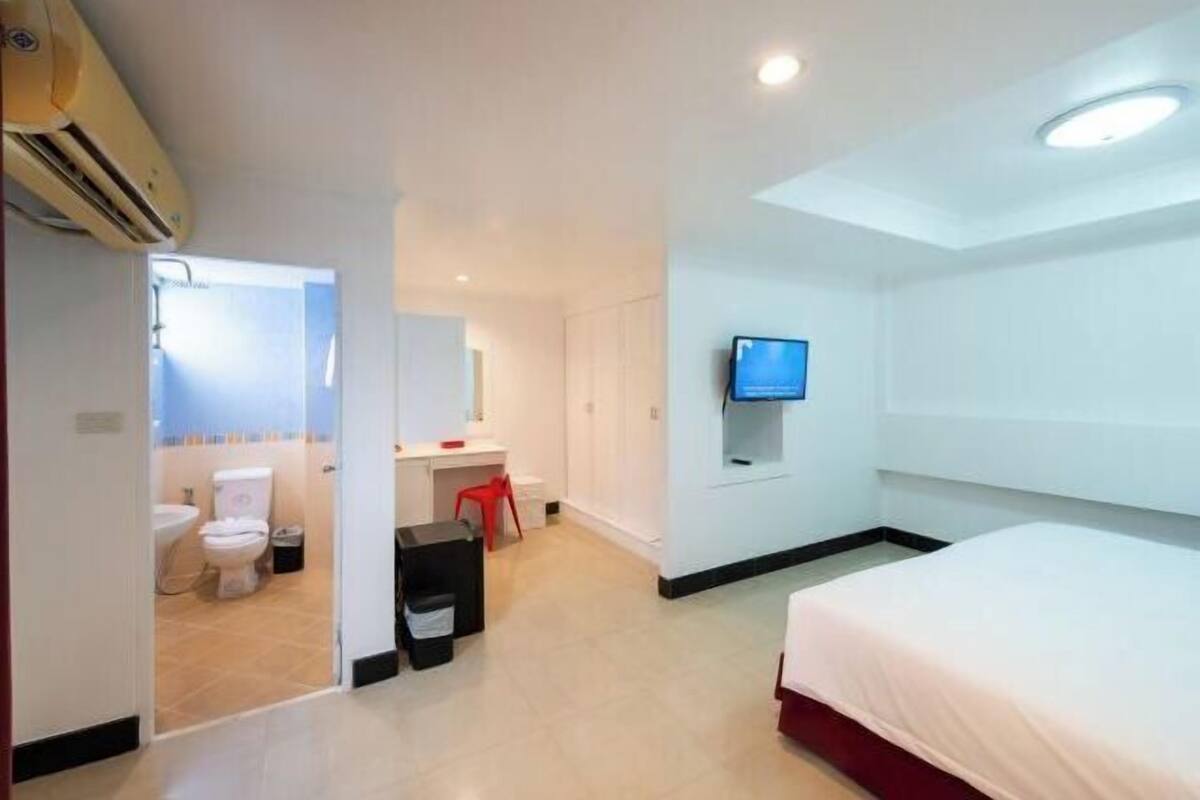 Ein Hotelzimmer mit Bett, Fernseher, Schreibtisch und einem Badezimmer mit Toilette und Waschbecken.