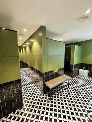 A modern restroom with green walls, a patterned floor, and a bench. - Yuanjili International Youth Hostel (Qingdao)