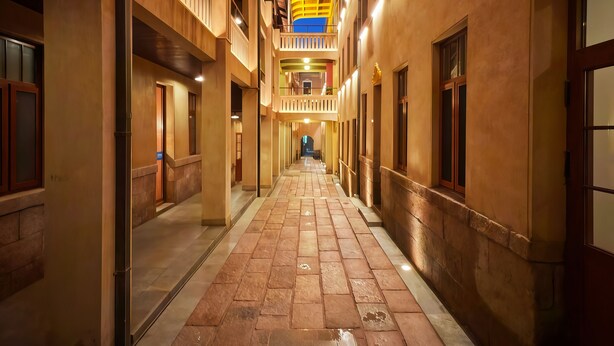 A corridor with multiple floors, each with balconies and windows. The corridor is paved with stone tiles and has a central open space. - Yuanjili International Youth Hostel (Qingdao)