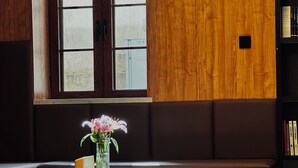 A room with a wooden bench, a small wooden table with a vase of flowers, and a bookshelf. - Yuanjili International Youth Hostel (Qingdao)