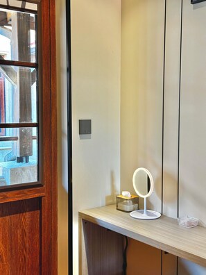 A bathroom with a wooden vanity, a mirror with a light, and a tissue box. - Yuanjili International Youth Hostel (Qingdao)