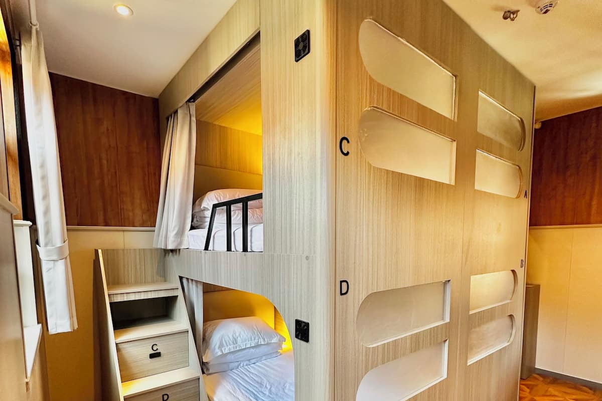 A compact, multi-level room with a bunk bed, built-in storage, and a geometric patterned floor.