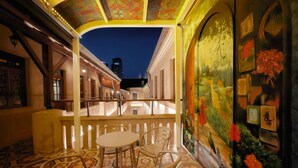 A cozy indoor seating area with a round table and chairs, a decorative ceiling, and a mural with a peacock. - Yuanjili International Youth Hostel (Qingdao)