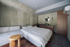 Ein modernes Schlafzimmer mit einem großen Bett, einem hölzernen Hocker, einer eingebauten Sitzbank, einem Schminktisch mit Spiegel und einem Kleiderschrank.
