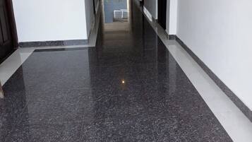 A corridor with a fire extinguisher mounted on the wall, a door on the right, and a window on the left.