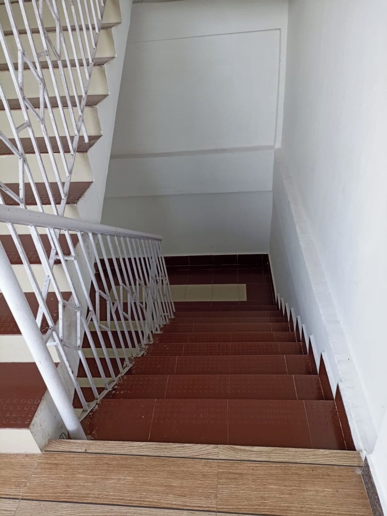 A staircase with white railings and brown steps.