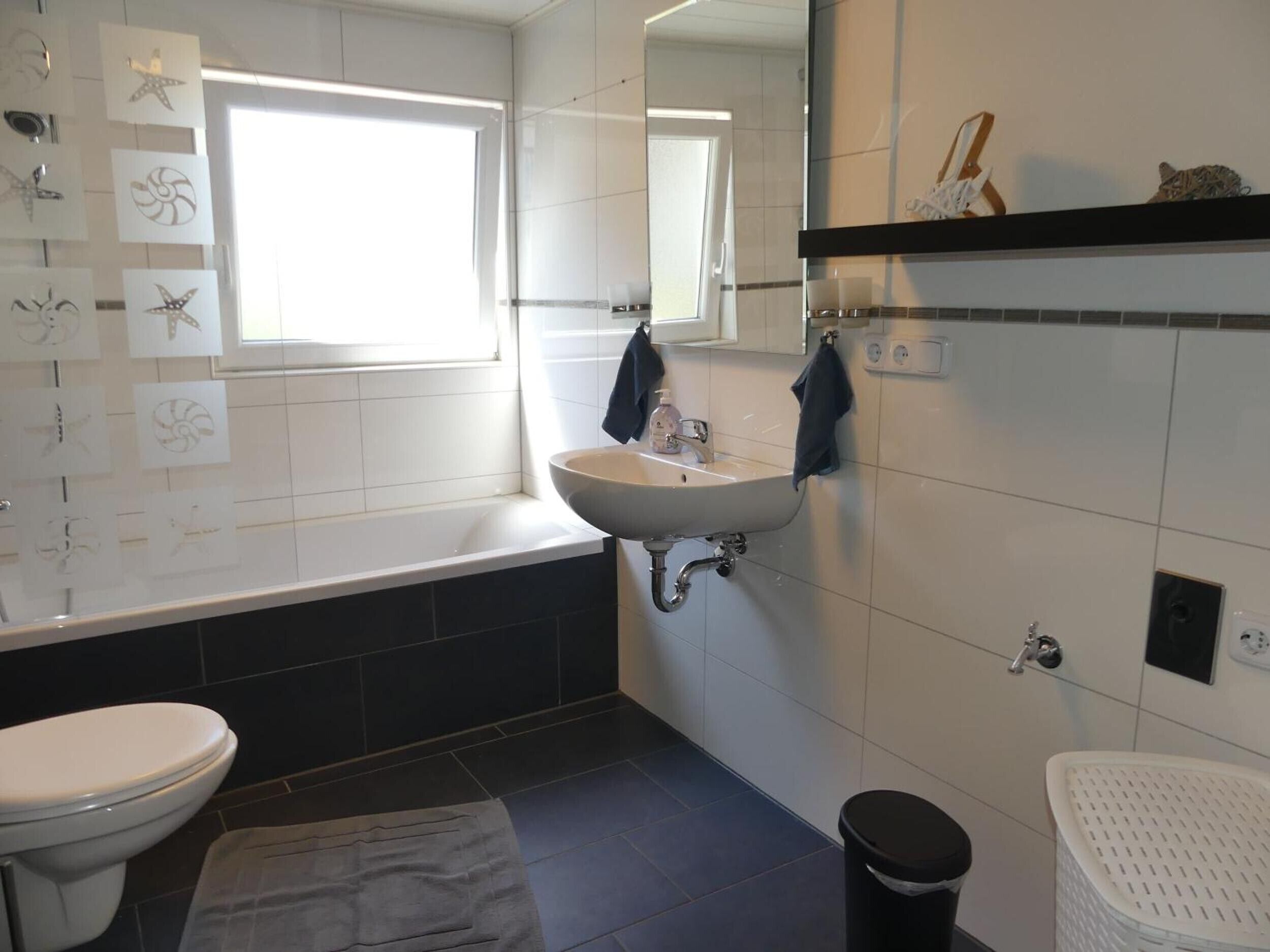 Ein Badezimmer mit einem weißen Waschbecken, einer Badewanne, einer Toilette und einem Mülleimer.