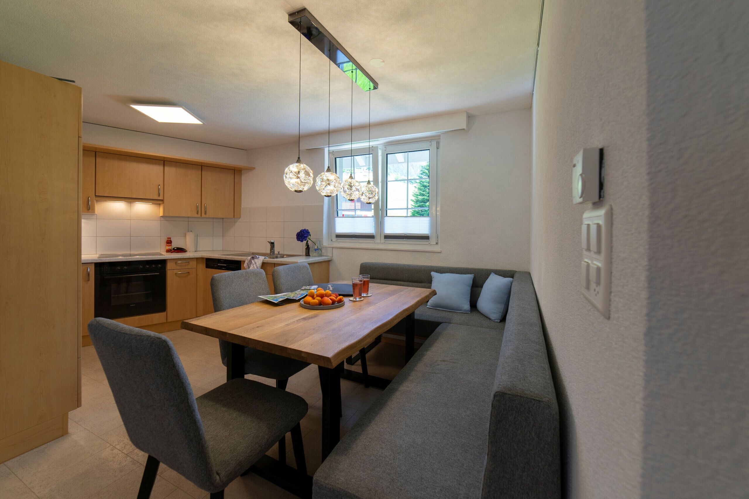 Una cocina moderna con armarios de madera, una mesa de comedor y una zona de estar con banco empotrado.