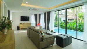 Una sala de estar moderna con un sofá, un televisor y vista a una piscina.