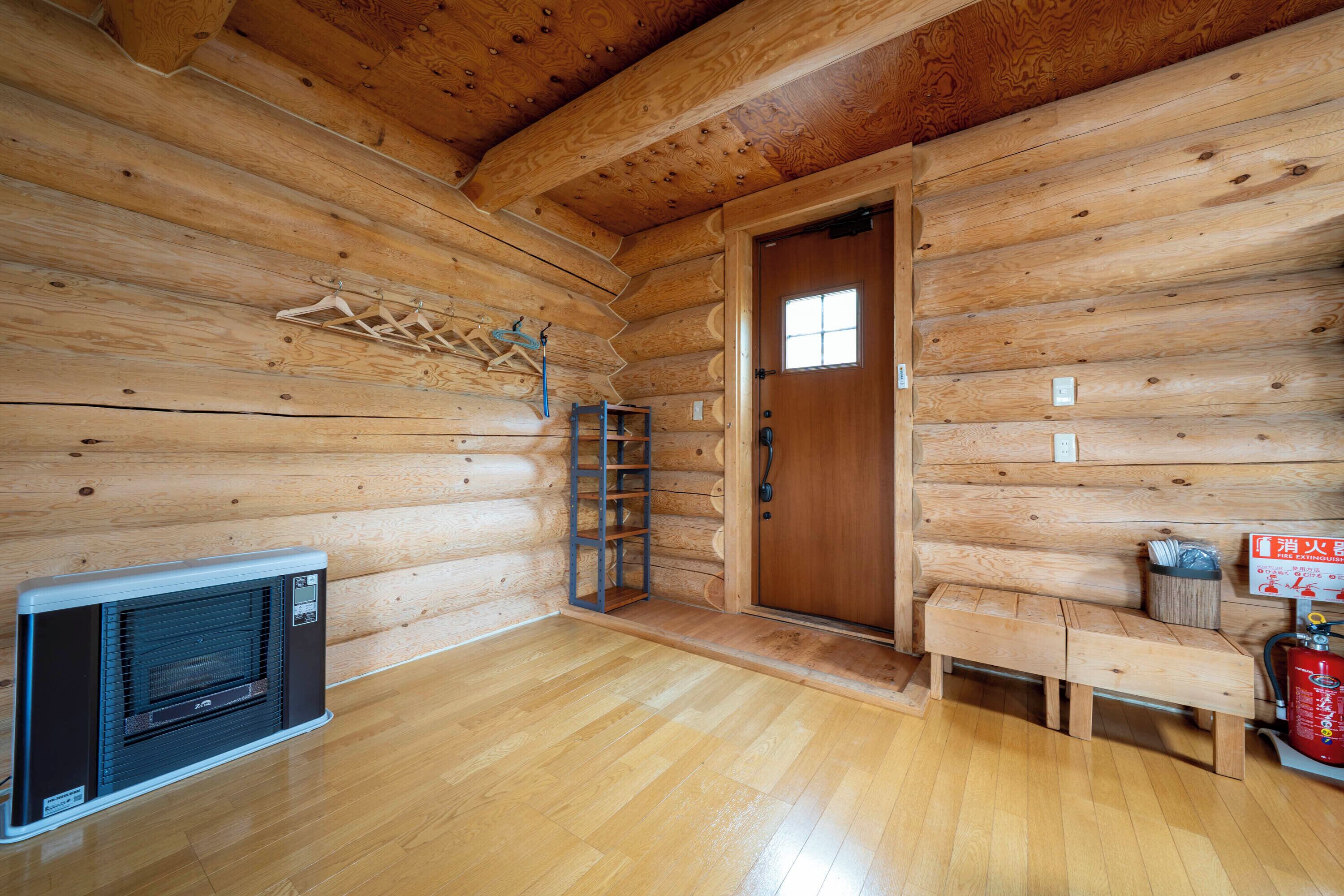 Interior de una cabaña de troncos con un banco de madera, un calentador y una escalera.