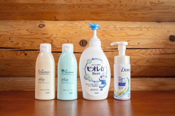 Cuatro botellas de productos de cuidado personal sobre una superficie de madera.