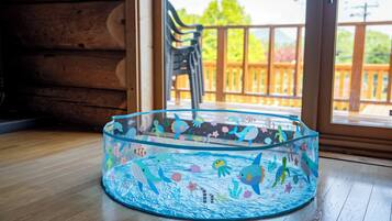 A round, clear fish tank with colorful sea creatures on a wooden floor near a window.