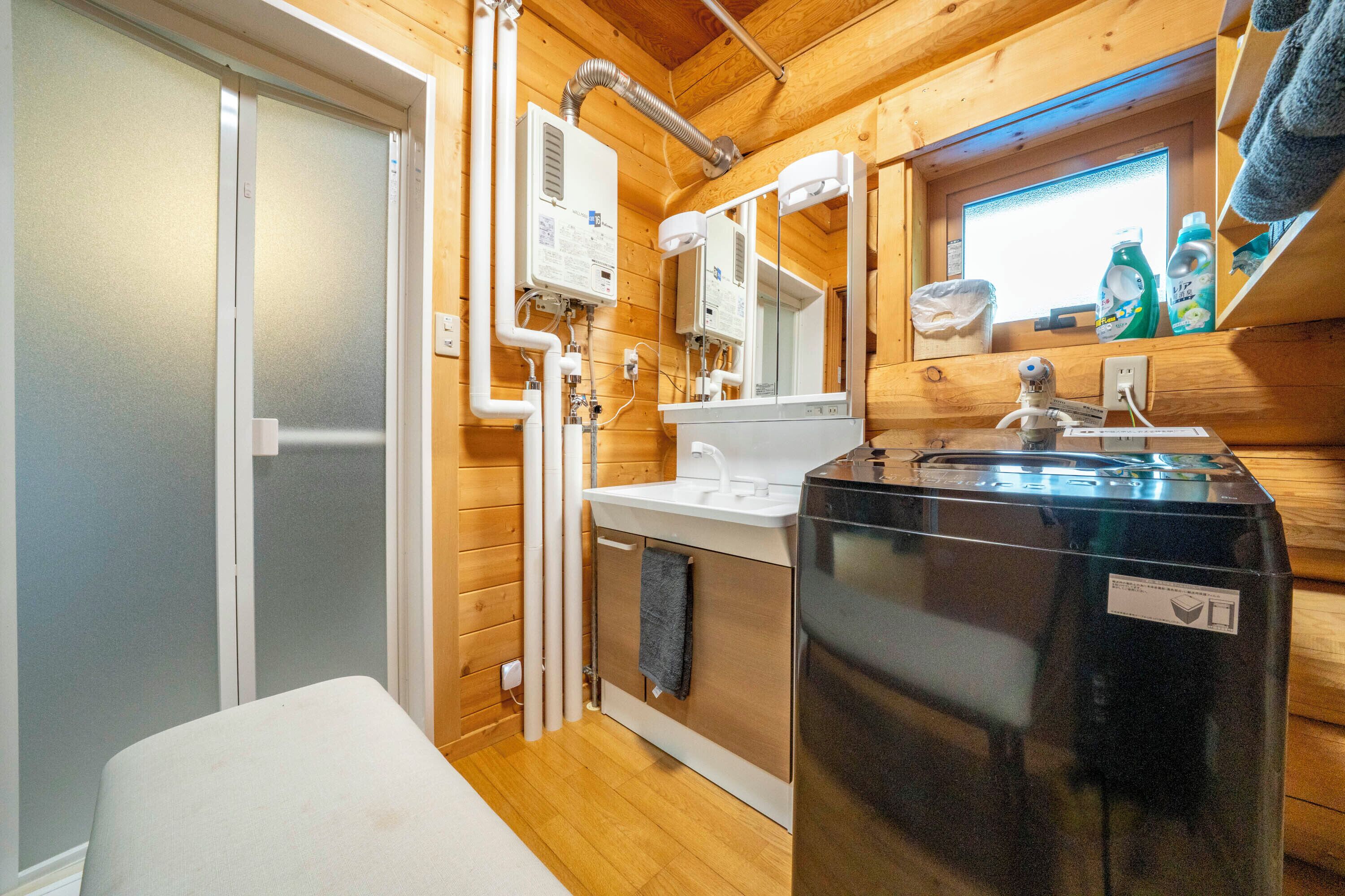 A compact bathroom with a sink, mirror, and a black washing machine.