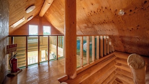 A wooden interior with a sloped ceiling, a fire extinguisher, and a view through a window to an outdoor area. - LAKE TOYA MOON HILLS (Toyako)