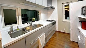 Eine moderne Küche mit weißen Schränken, einer Edelstahl-Spüle, einem Fenster und einem eingebauten Backofen.