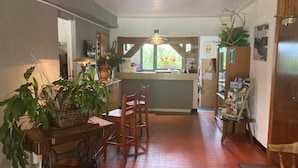 A cozy kitchen with a wooden table, chairs, and a window with a view of greenery. - HOTEL LA GRANGE (Boutx)