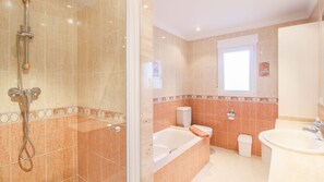 A bathroom with a glass-enclosed shower, a bathtub, a toilet, and a sink.