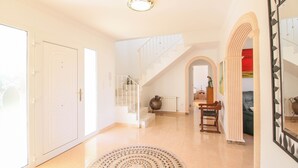 A spacious hallway with a staircase, a round rug, and a wooden bench. - Luxury Villa in Denia with sea views (Denia)