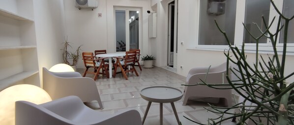 A patio area with a dining table and chairs, a small round table, and potted plants. - Palazzo Caratozzolo (Agrigento)