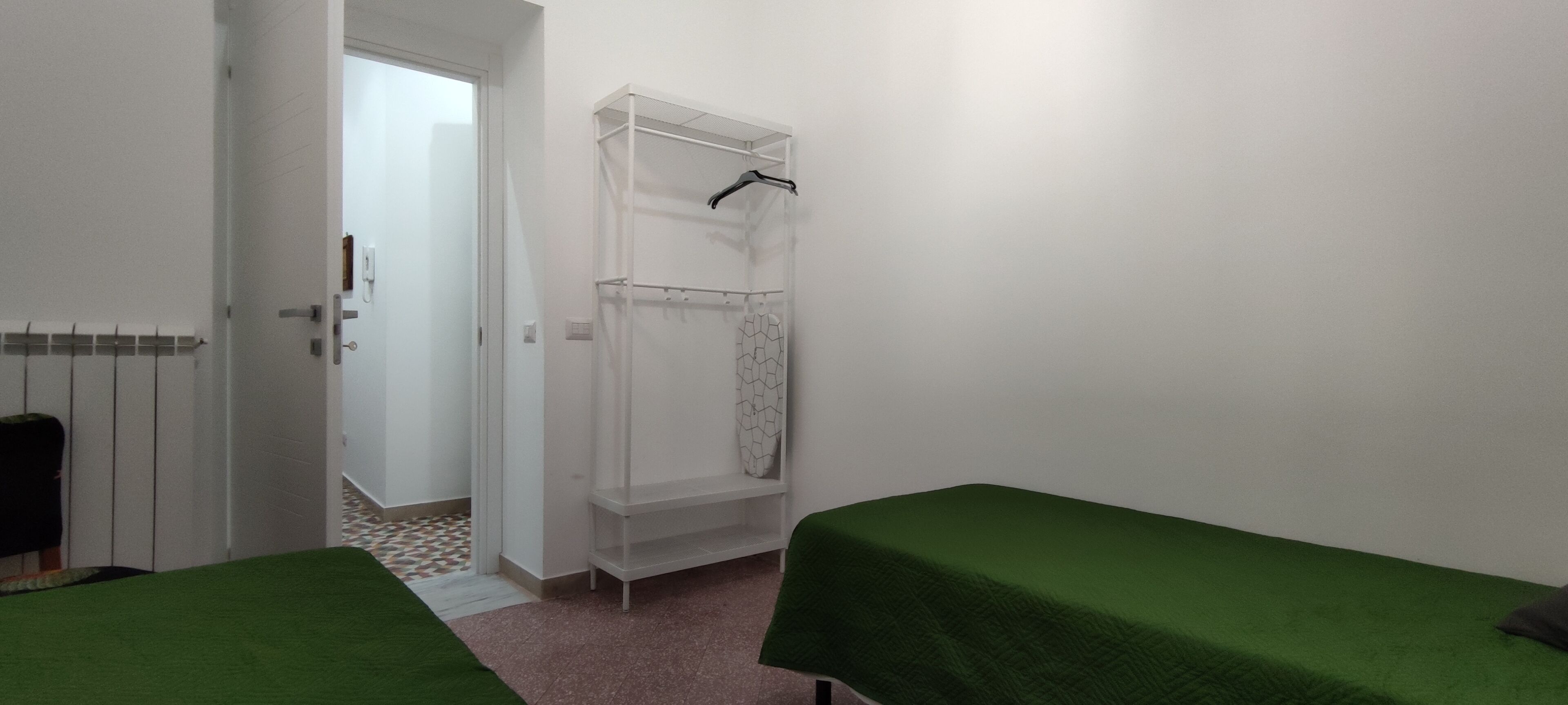 Una habitación pequeña y limpia con dos camas individuales, una zona de ducha y un radiador.