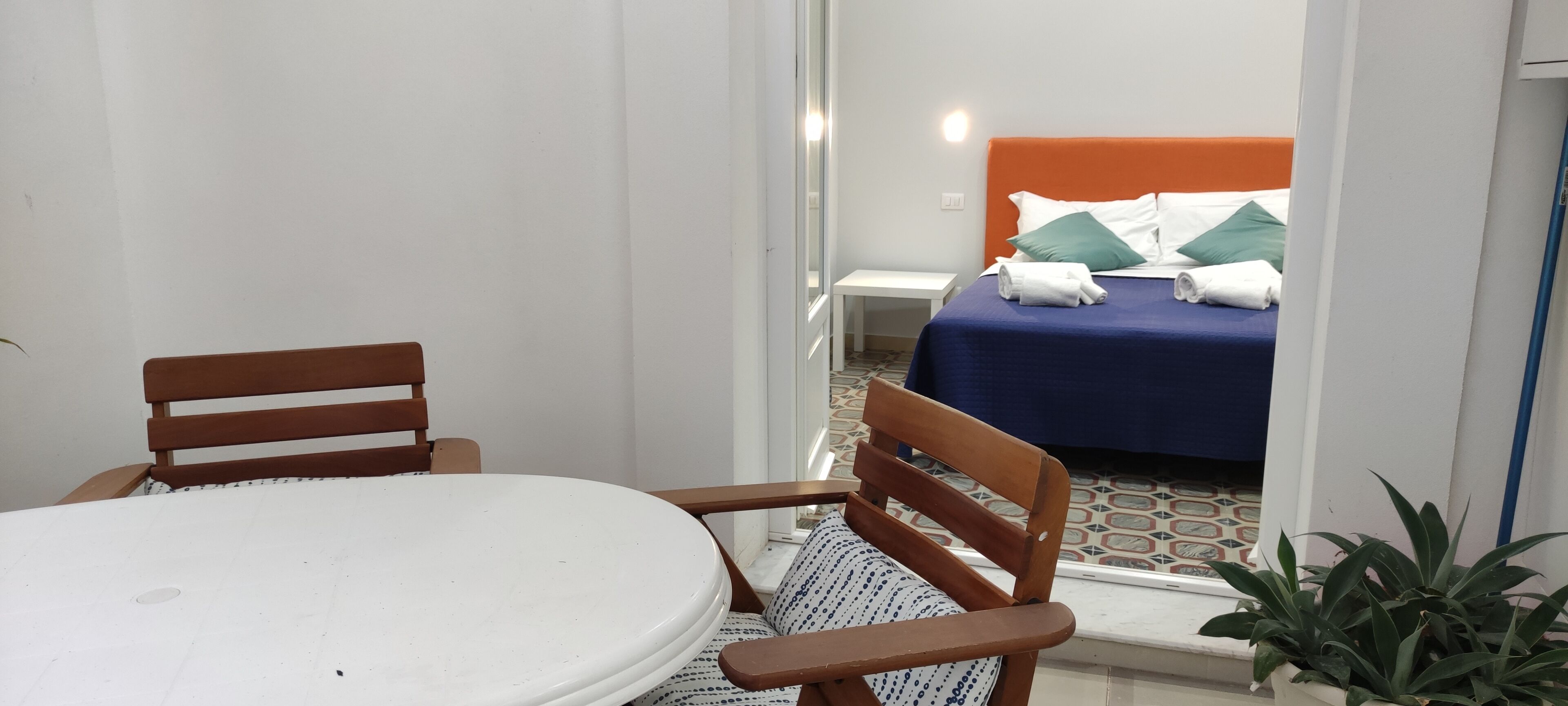 Quarto com cama, uma mesinha e duas cadeiras.