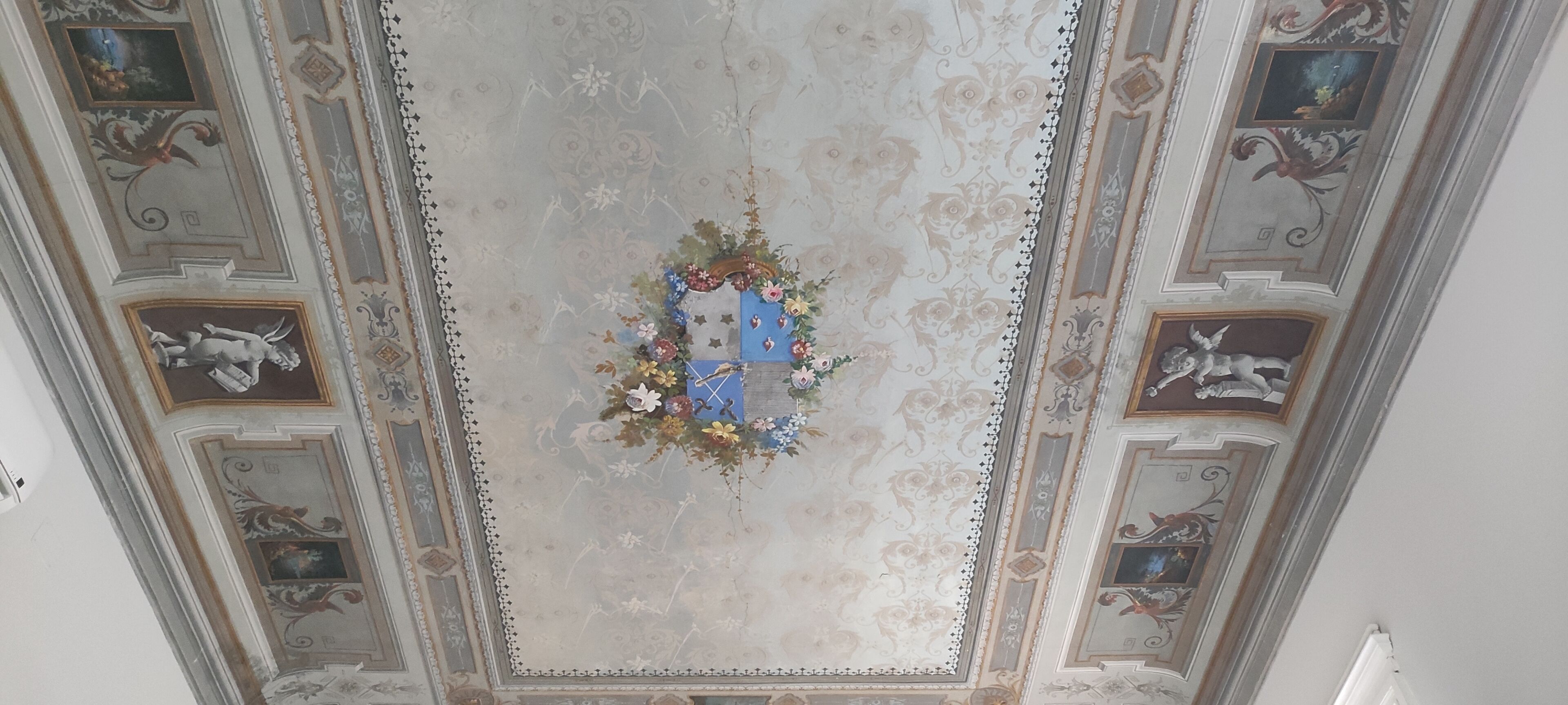 A ceiling with ornate decorations, including floral arrangements and classical motifs.