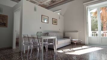 Een kamer met een witte bank, transparante stoelen, een klein tafeltje en een vloer met een patroon.