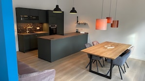Una cocina moderna con armarios oscuros, una isla central e iluminación colgante.