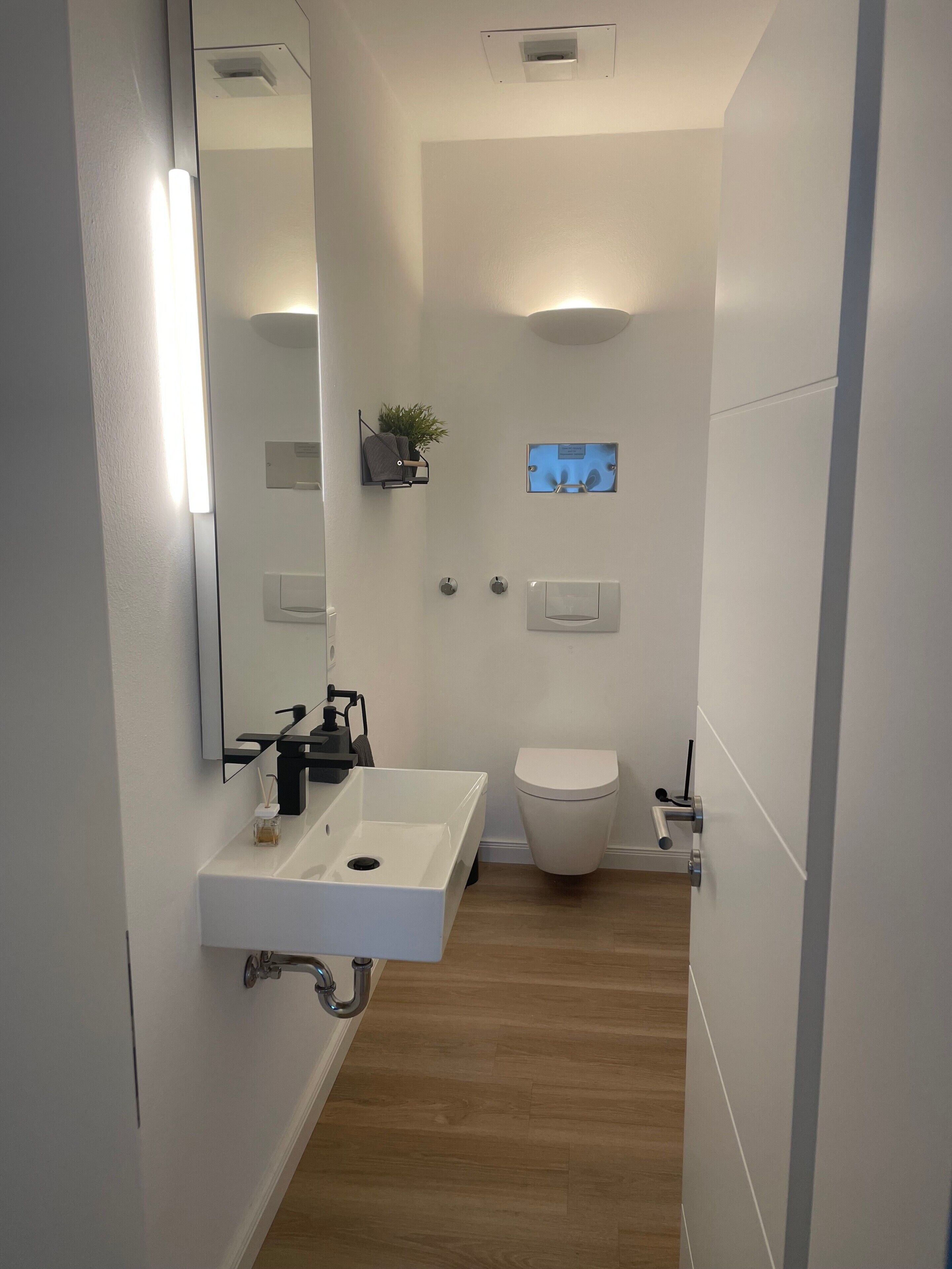 A modern bathroom with a white sink, toilet, and shower.