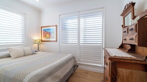 A bedroom with a bed, a dresser, and a painting on the wall. - Roomy Duplex with water views. Steps  away from Castle Rock Beach (Clontarf)