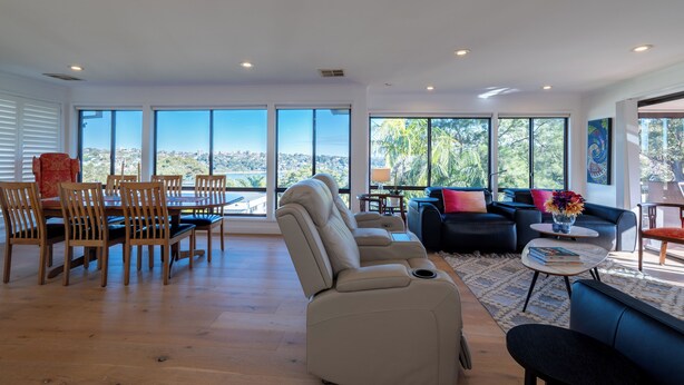 A spacious living area with a dining set, seating, and large windows offering a city view. - Roomy Duplex with water views. Steps  away from Castle Rock Beach (Clontarf)