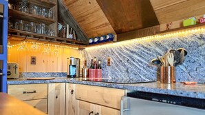 A kitchen with wooden cabinets, a granite countertop, a coffee maker, and a wine cooler. - Downtown Boothbay Harbor Studio – Ocean Views, Dog-Friendly, Walk to Pier (Boothbay Harbor)