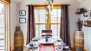 A dining area with a wooden table set for four, a chandelier, and wooden barrels as decor.