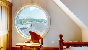 A bedroom with a skylight window, a wooden chair, and a bed with a wooden headboard.