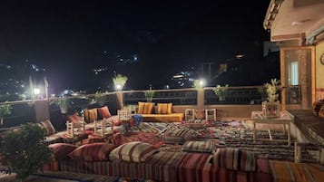 A rooftop terrace with outdoor seating, including sofas and chairs, and a small table.