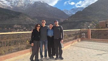 Un grupo de personas en una terraza en la azotea, con un paisaje montañoso al fondo.