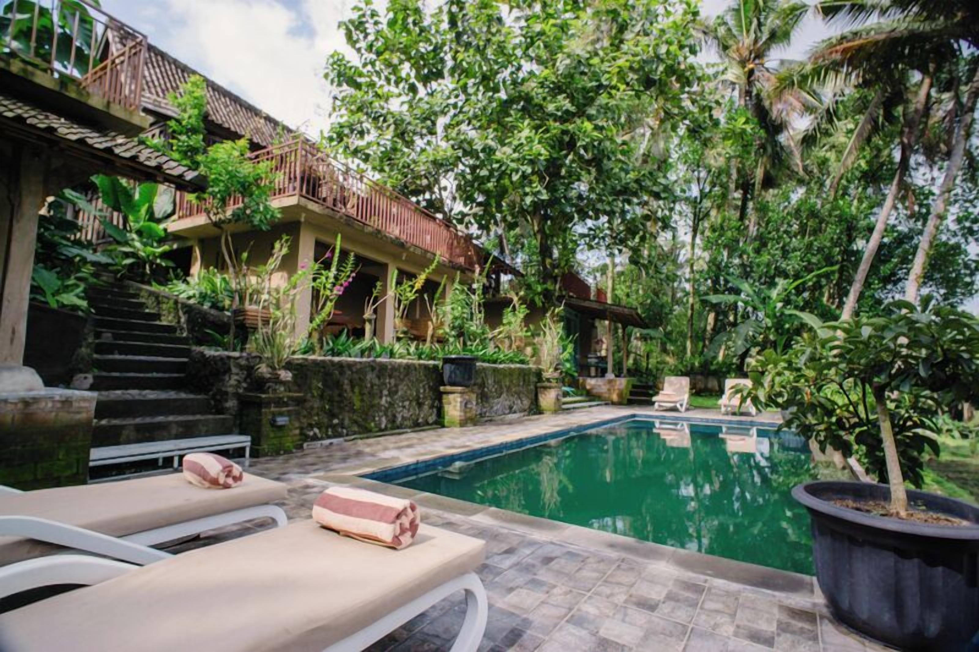 A pool area with lounge chairs and a staircase leading to a building.
