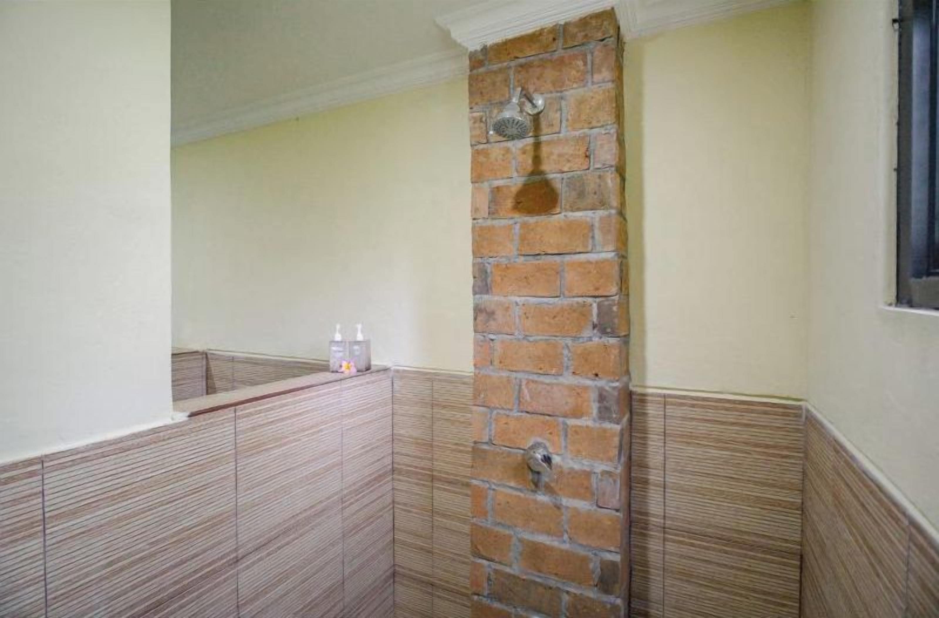 Un baño con zona de ducha, lavamanos y ventana.