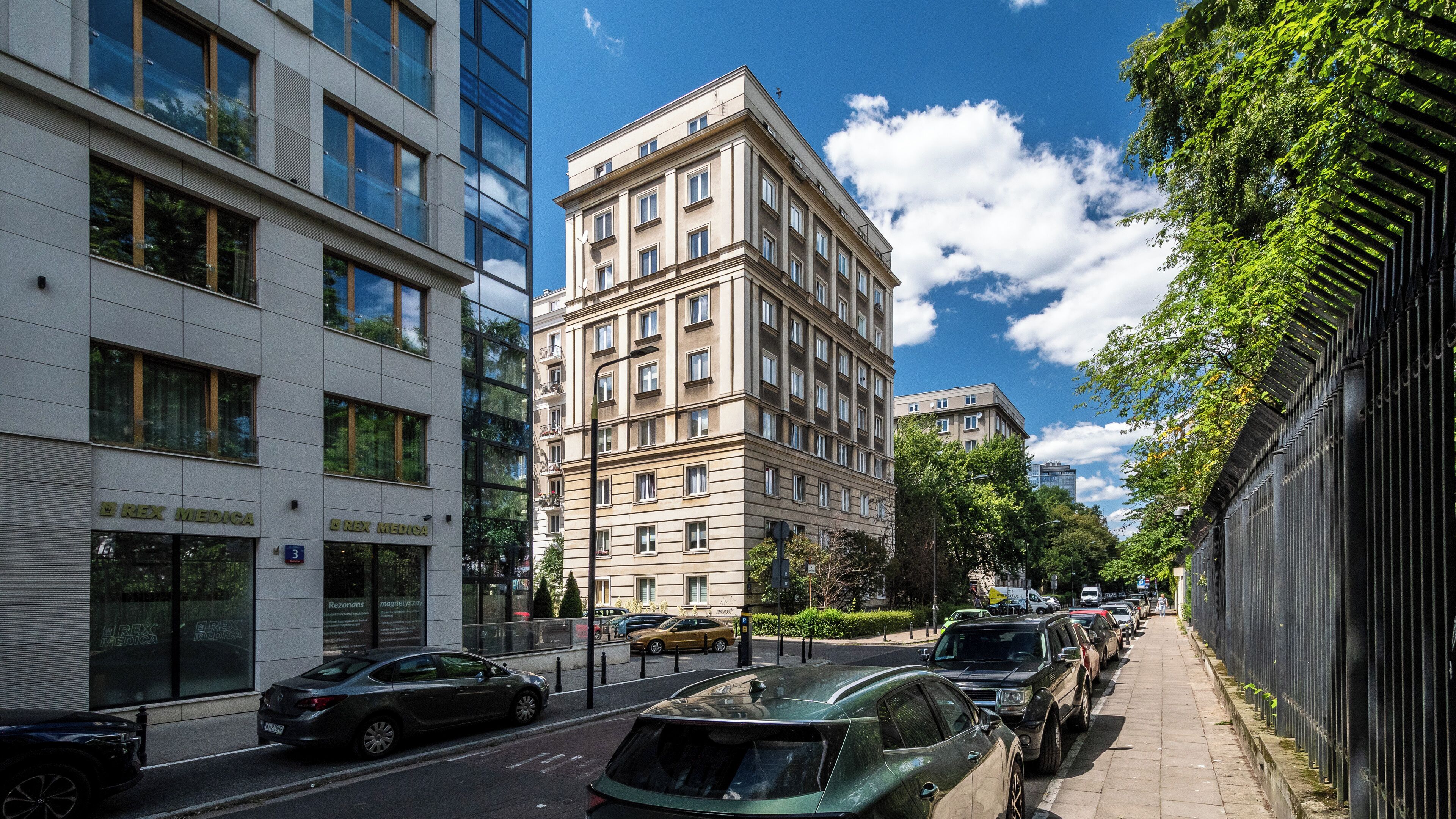 Vista urbana con edificios modernos, coches aparcados y cielo despejado.