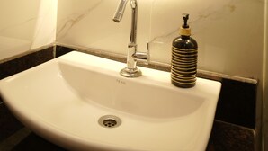 Un baño con un espejo redondo, un lavamanos blanco y un dispensador de jabón.