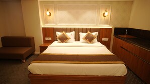 Habitación de hotel con una cama grande, dos mesitas de noche, un cabecero de madera y dos lámparas fijadas a la pared.