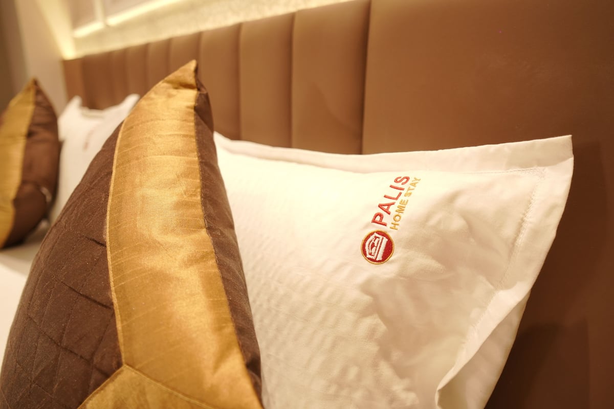A close-up of a bed with a headboard and pillows.