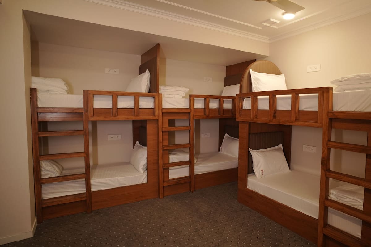 A room with four bunk beds, each with a wooden frame and white bedding.