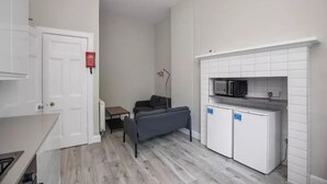 Et lille køkken med mikrobølgeovn, minikøleskab og sofa.