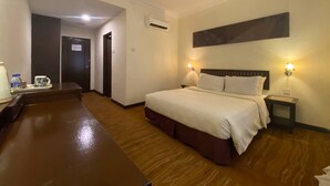 A hotel room with a bed, bedside lamps, a desk, and a coffee maker.