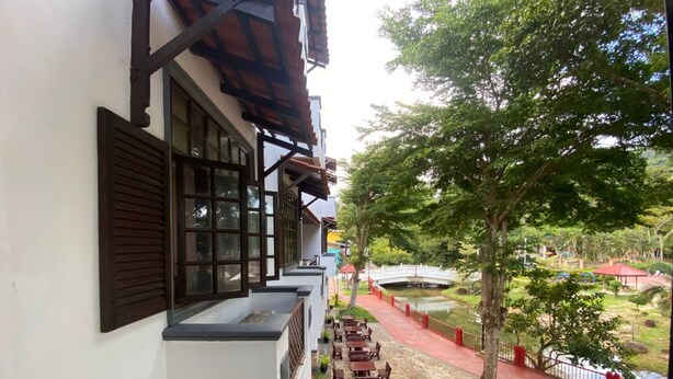 A building with a balcony, outdoor seating, a bridge, and a pond.