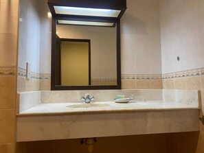 A bathroom with a sink, mirror, and a light fixture above the mirror. - Capital O 91179 Geopark Oriental Village (Langkawi)